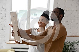 Couple hanging photo frame during relocation day at new home