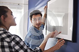 Couple hanging a picture frame on the wall