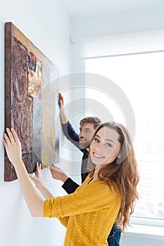 Couple hanging picture on the wall