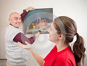 Couple hanging picture on wall at. Focus on girl