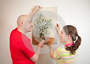 Couple hanging up an art picture on their wall