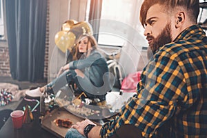 Couple with hangover sitting in messy room