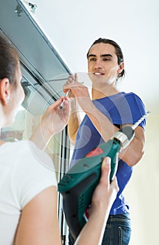 Couple hangs curtains on window