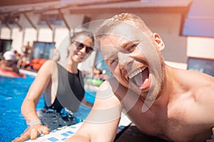 Couple happy caucasian beautiful young woman and man make selfie photo on background swimming pool. Concept travel