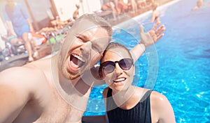 Couple happy caucasian beautiful young woman and man make selfie photo on background swimming pool. Concept travel