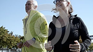 Couple of happy older runners jogging down street