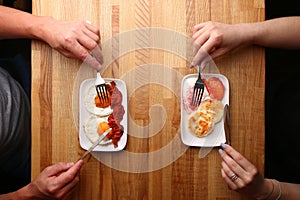 Couple have breakfast on wood table cheese pancake with sour cream and fried egg with bacon top view