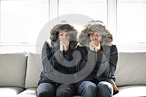 Couple have cold on the sofa at home with winter coat