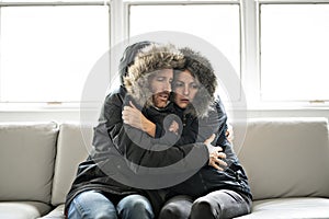 Couple have cold on the sofa at home with winter coat