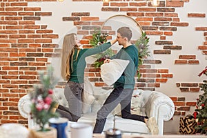 Couple have fun and do pillow fight in room. Christmas decor. Concept of family and Christmas