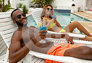 Couple having cocktail drink while relaxing on a sun lounger