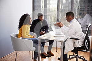 Couple Having Consultation With Male Doctor In Hospital Office