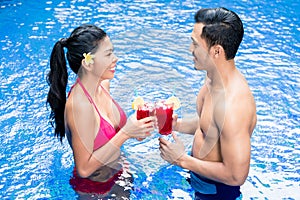 Couple having drinks in pool in Asia