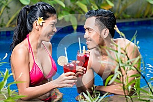 Couple having drinks in pool in Asia