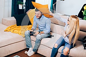 Couple having fun in apartment, attractive couple engaged in a pillow fight during online games dispute