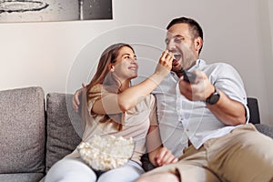 Couple having fun eating popcorn and watching TV at home