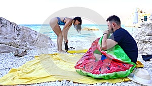 couple having fun inflate inflatable mattress at sea beach