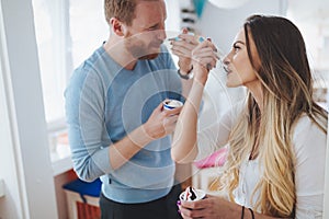 Couple having fun and laughing at home while eating ice cream