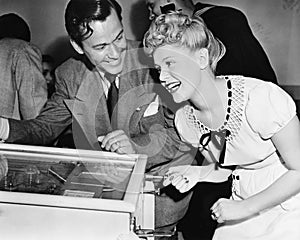 Couple having fun and laughing next to a pinball machine photo