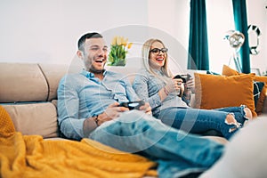 Couple having fun and laughing while playing video games in modern living room