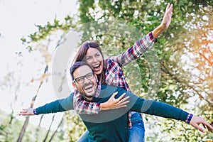 Couple having fun man giving piggyback to woman in park