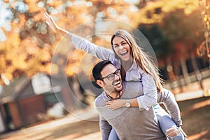 Couple having fun man giving piggyback to woman in park