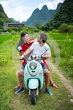 Couple having fun on motorbike around rice fields in China