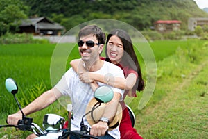 Couple having fun on motorbike around rice fields in China