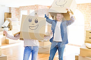 Couple having fun at new apartment wearing boxes with funny faces over head