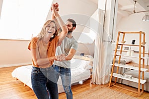 Couple Having Fun In New Home Dancing Together photo