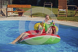 Couple having fun playing with squirt guns at the swimming pool