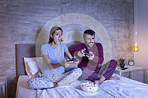 Couple having fun playing video games in bed