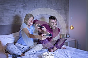 Couple having fun playing video games in bed at night