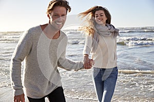 Couple Having Fun Running Along Winter Beach Together