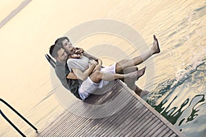 Couple having fun seated on a boardwak with a beautifull lake view