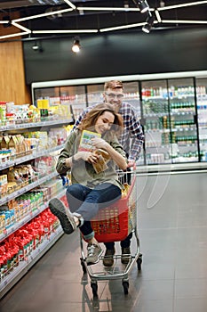 Couple having fun with the shopping cart in the supermarket