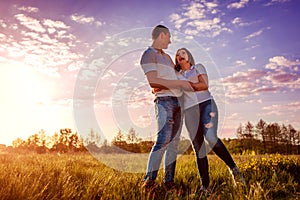 Couple having fun in spring field. Young man and girl hugging and laughing at sunset.