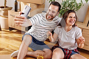 Couple having fun taking selfies with their new apartment keys while moving in together