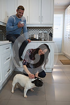 Couple having fun with their pet dog in kitchen