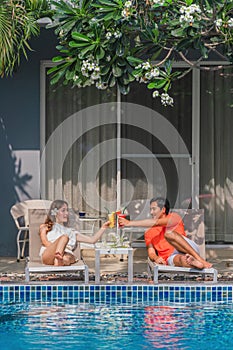 Couple having goodtime together on summer vacation in resort and hotel garden beside pool