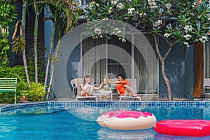 Couple having goodtime together on summer vacation in resort and hotel garden beside pool photo