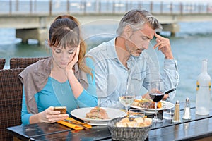 Couple having meal both preoccupied with cellphones photo