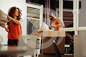 Couple having pillow battle while moving to new apartment