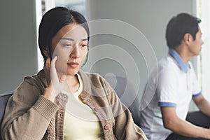 couple having relation problem. Wife sad and sitting separate with her husband at home after quarrel