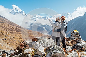 Couple having a rest on Everest Base Camp trekking route near Dughla 4620m. Backpackers left Backpacks, embracing and enjoying