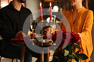 Couple having romantic dinner in restaurant, focus on bouquet of roses