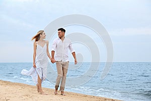 Couple having romantic walk on beach. Space for text