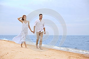 Couple having romantic walk on beach. Space for text