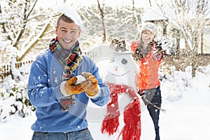 Couple Having Snowball Fight In Garden