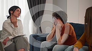 Couple having therapy session with a psychologist to solve their relationship problems and crisis. Sad man covering his